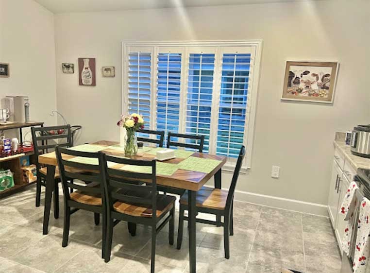 Kitchen with a dining table and chairs set in front of a window with blinds.